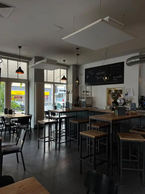 Heller Gastraum des Café Heidelberg Hildesheim mit Hochtischen, Holztischen und großen Fenstern