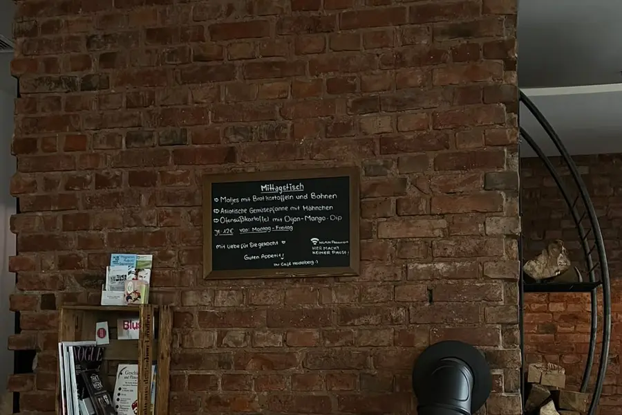 Backsteinwand mit Kaminofen und der Kreidetafel für den Mittagstisch im Café Heidelberg