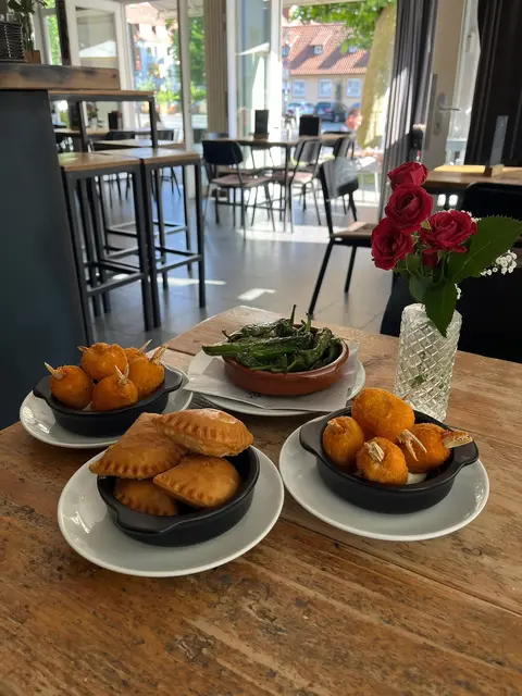 Tapas im Café Heidelberg: Empanadas, Kroketten und gebratene Pimientos auf einem Holztisch