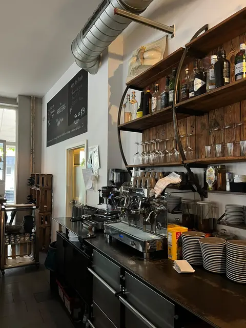 Theke des Café Heidelberg mit Siebträgermaschine und Regal voller Weinflaschen